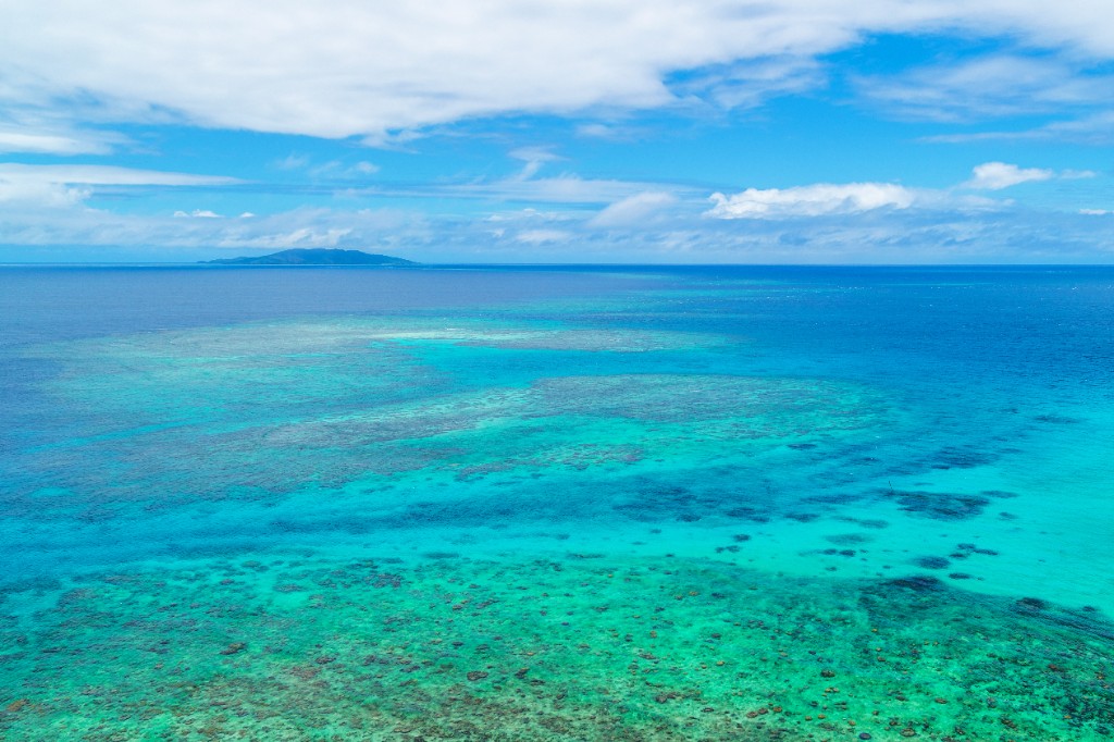 Aerial view of tropical Fiji ocean, coral reef, and distant island