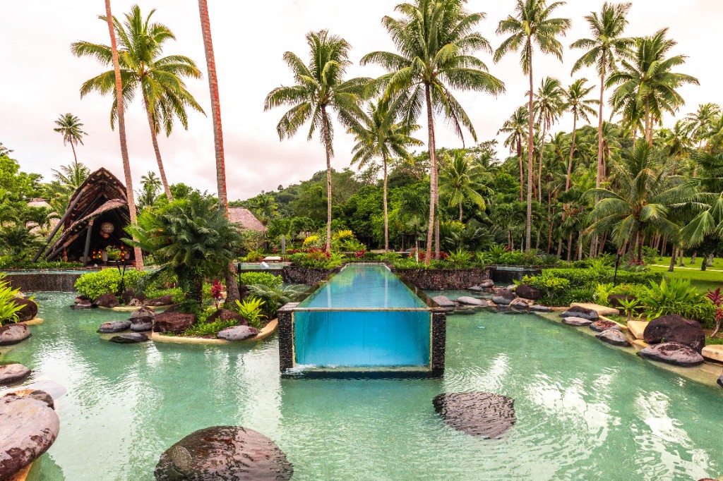 Tropical Fiji resort infinity pool with glass walls and palm trees